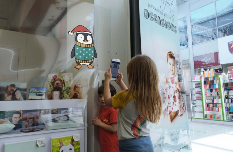 A child scans the QR code of a festive penguin character