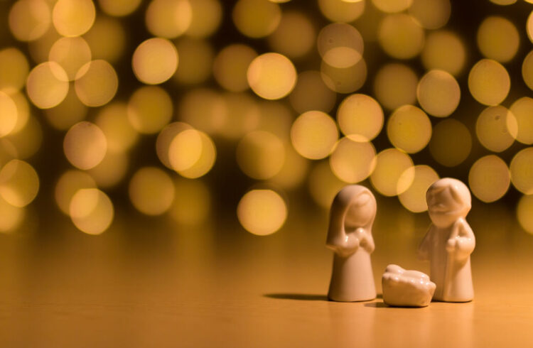 Small figures of Mary, Joseph and baby Jesus in front of golden lights