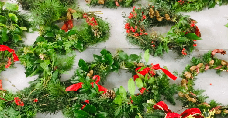 Christmas Wreaths laid on a table with red festive ribbons