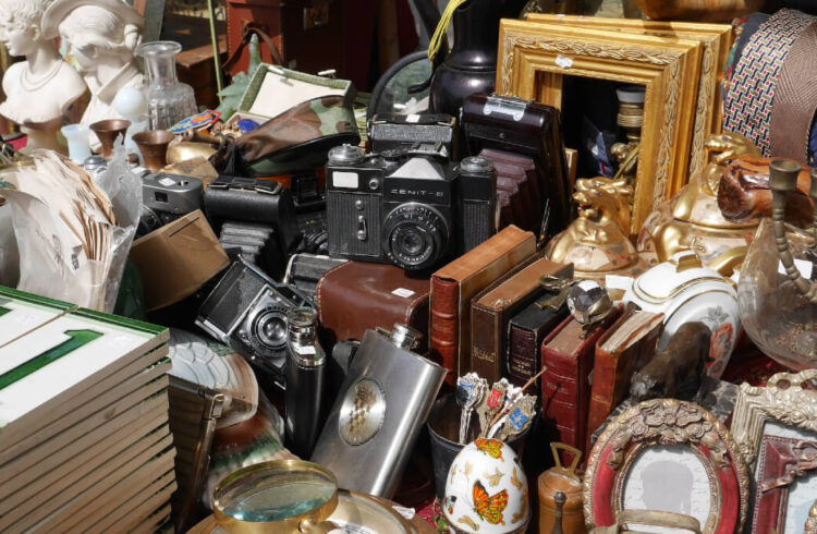 A stall at a flea market filled with items to sell, tiles, picture frames, bits and bobs.