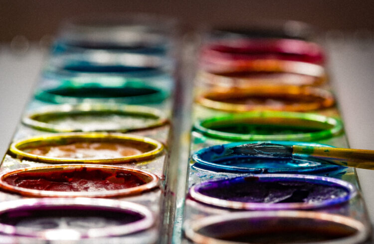 A close up of a colourful paint palette and a paint brush