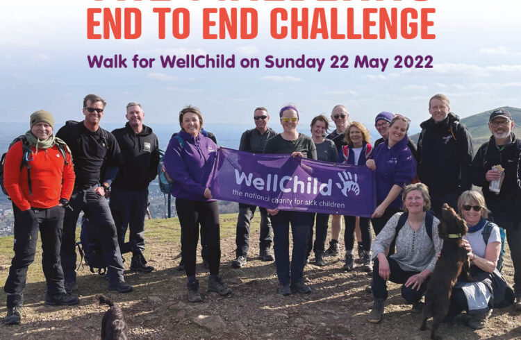 15 walkers and 2 dogs on the top of the Malvern Hills holding a banner of WellChild.