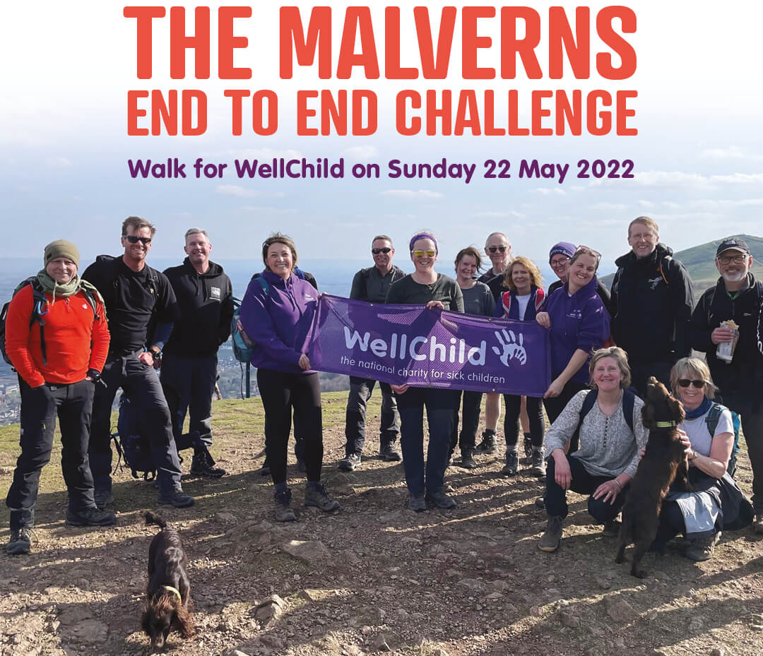 15 walkers and 2 dogs on the top of the Malvern Hills holding a banner of WellChild.