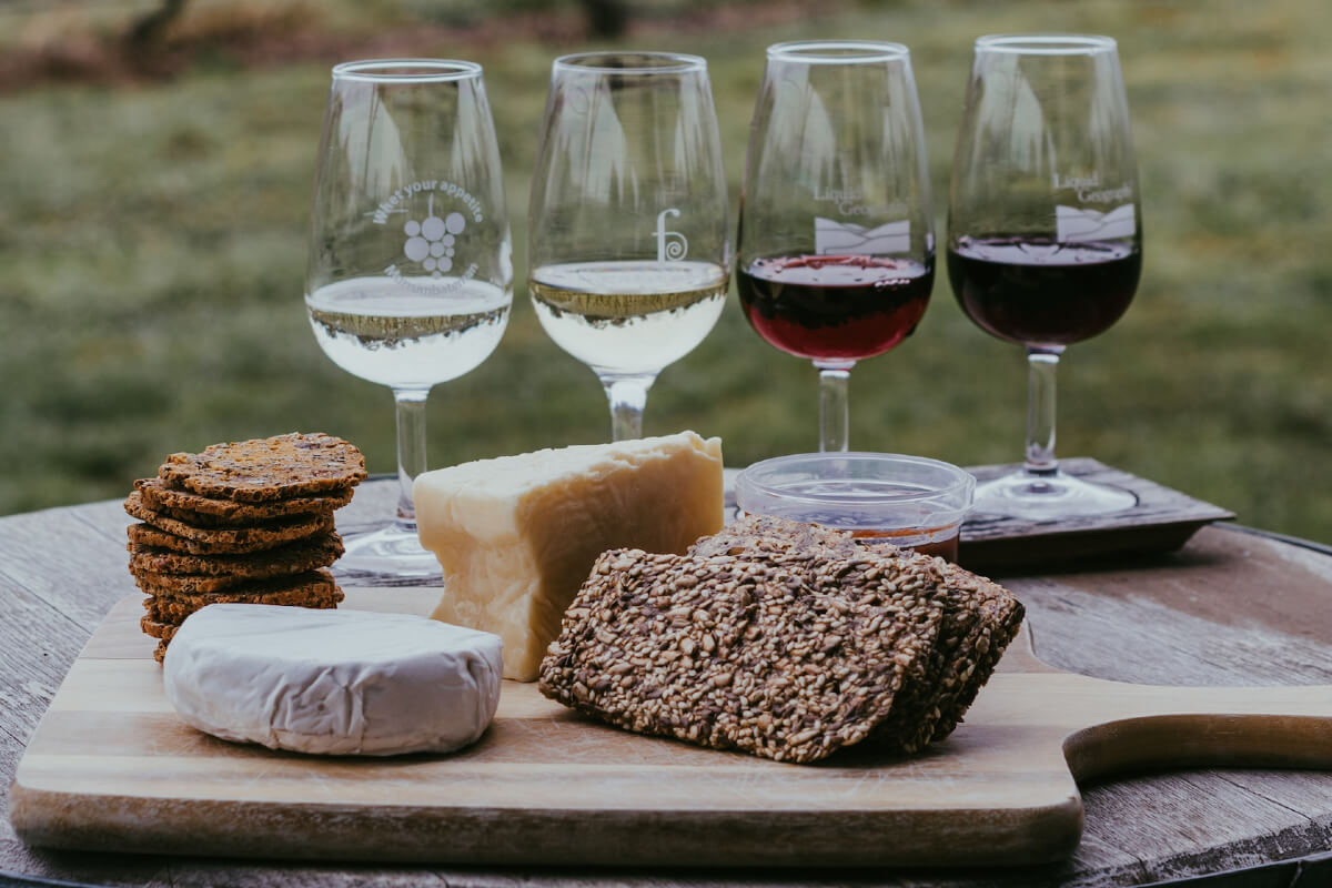 4 wine glasses with different coloured wines, and nibbles infront.