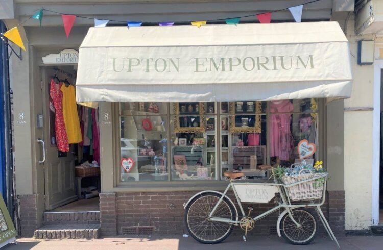 pretty shop with sage green pain, awnings and decorative bike out front