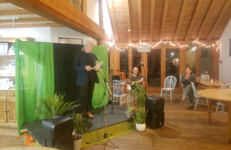 a man performing on a small stage in a timber building in front of an audience