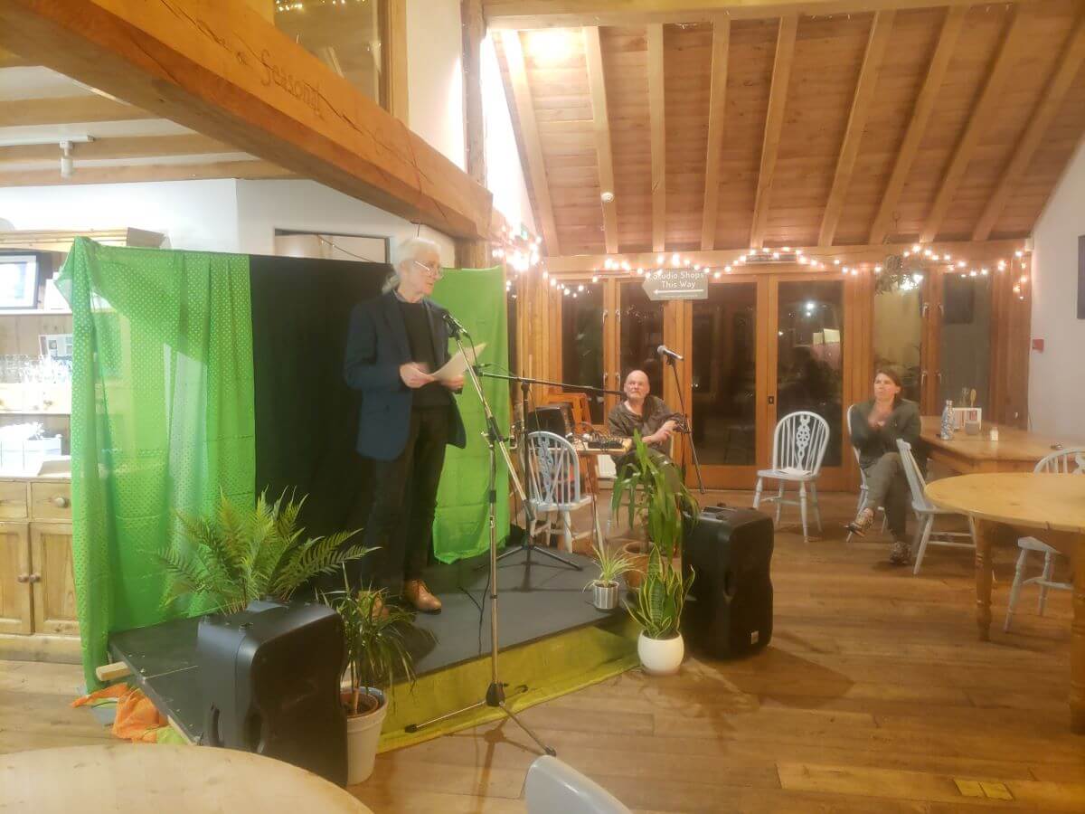 a man performing on a small stage in a timber building in front of an audience