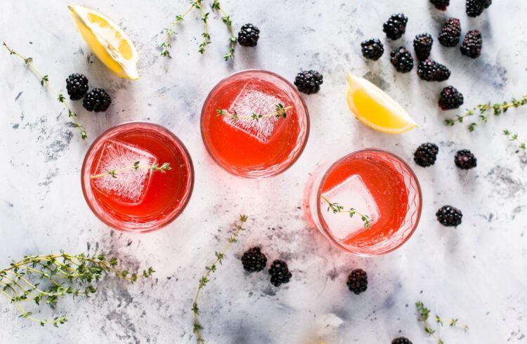 three glasses of a pink drink seen from above on a marble surface surrounded by fruit