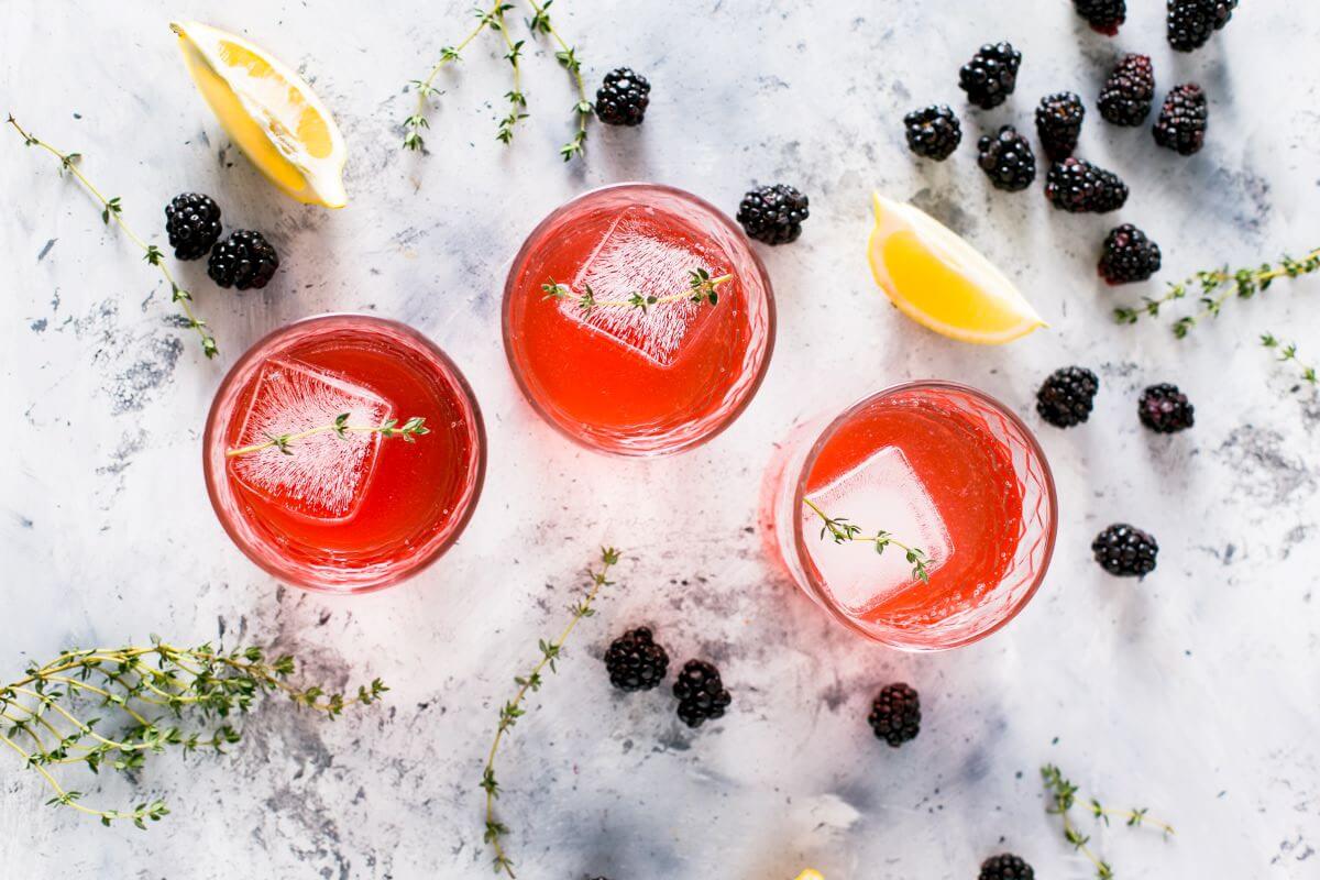 three glasses of a pink drink seen from above on a marble surface surrounded by fruit