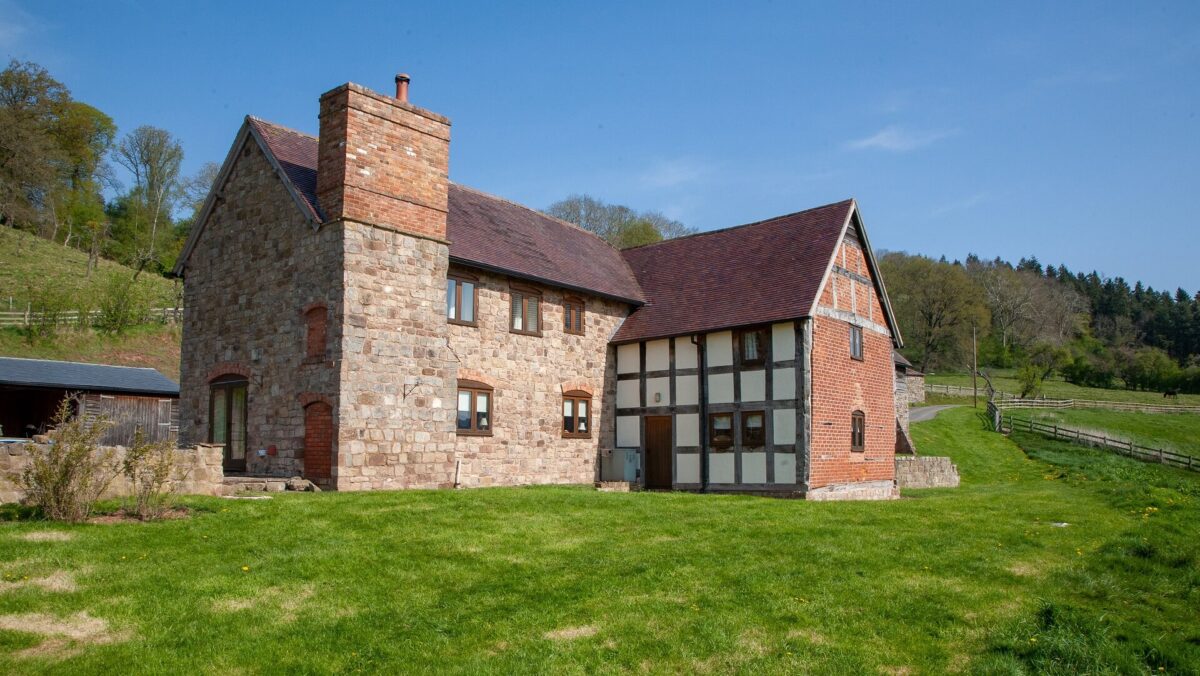 Exterior view of part-timber-framed cottage with grass around