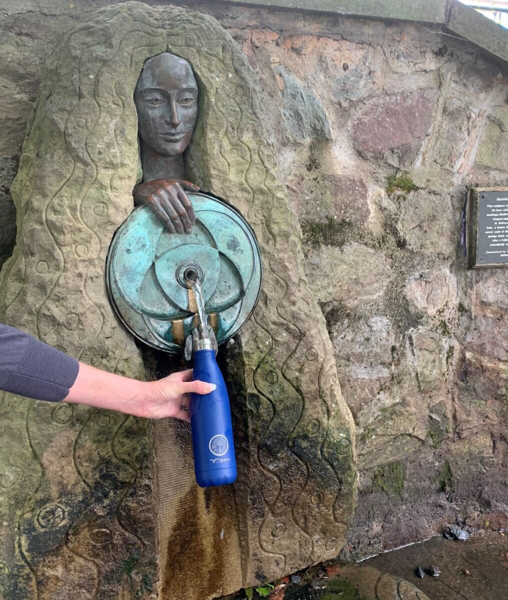 a water fountain shaped like a woman fills a reusable water bottle