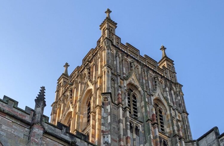 A view of Great Malvern Priory tower with blue sky in the background