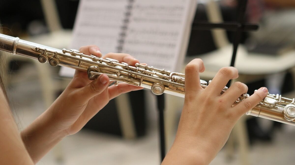 A woman playing a flute with a music stand in the background