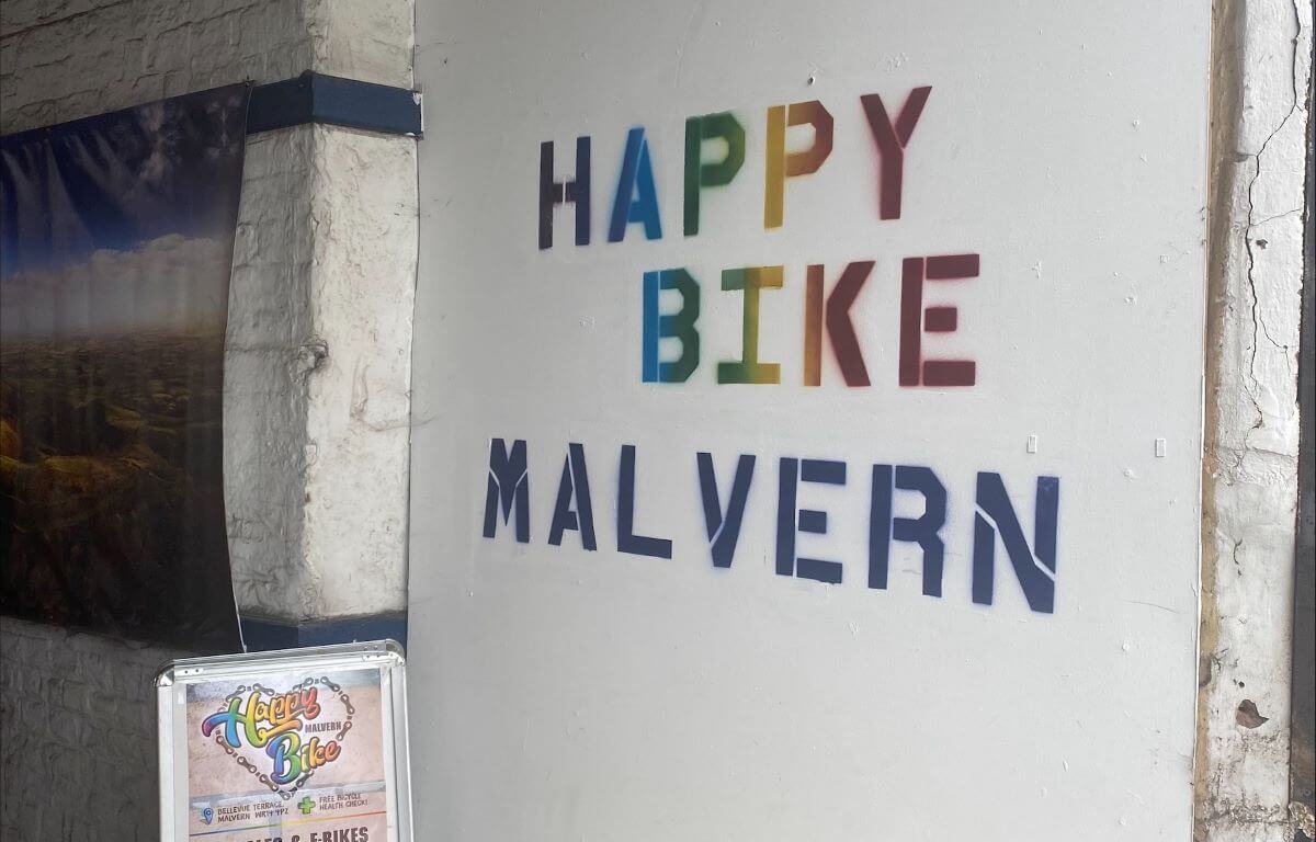 Rainbow writing on a white wall that spells happy bike