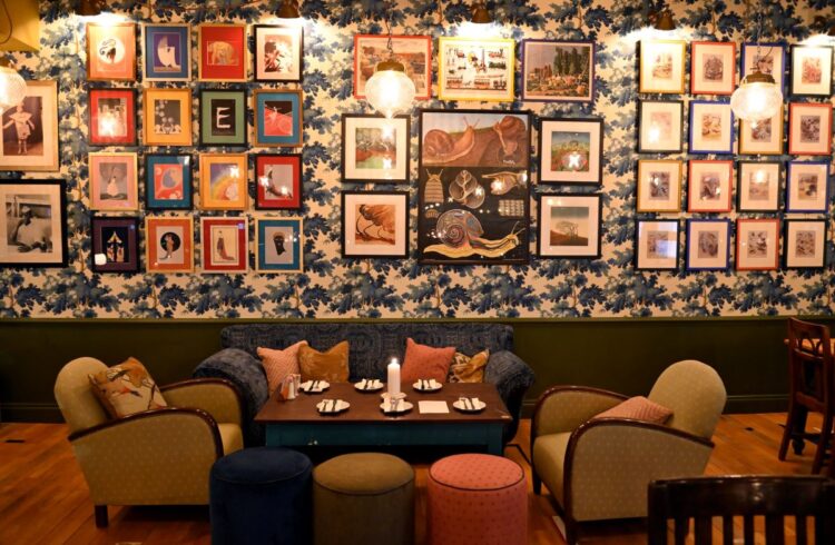 Vintage style restaurant interior with comfortable armchairs, low lighting and gallery wall