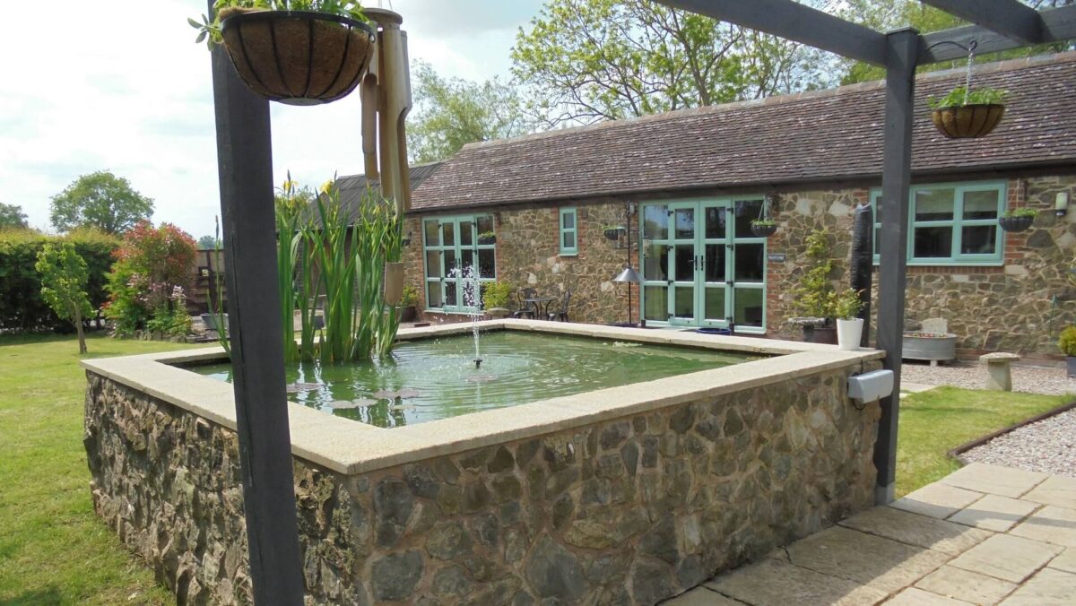 Outside area at Beech Lodge with pond, hanging baskets, grass