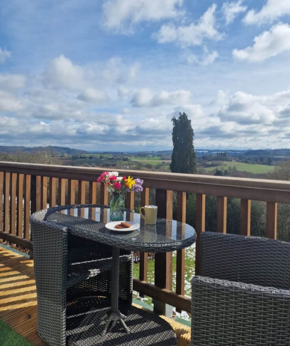 Two chairs and a table on a veranda over looking the English counryside