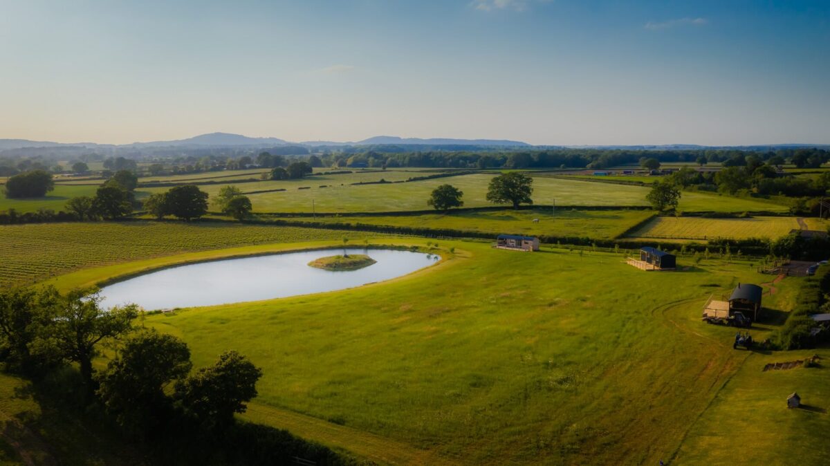 Aerial view of Wagtail Retreat with pool in field and hills in background