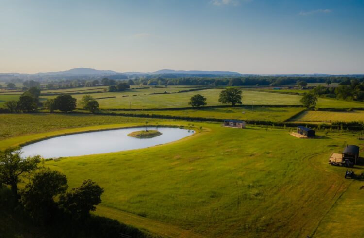 Aerial view of Wagtail Retreat with pool in field and hills in background