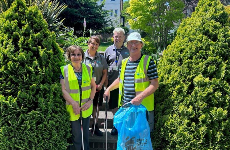 Four wearing hi-vis people hold litter picks