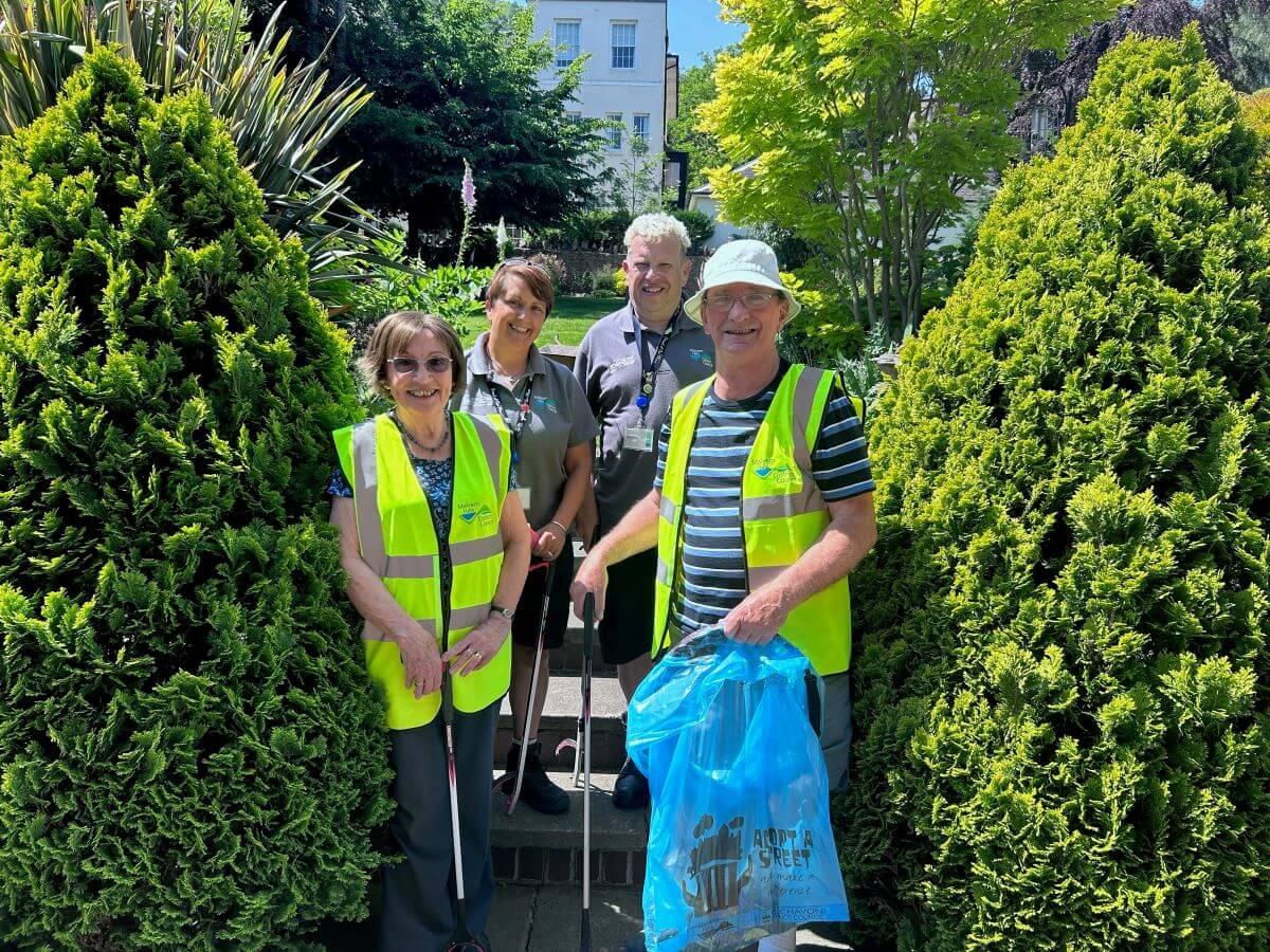 Four wearing hi-vis people hold litter picks