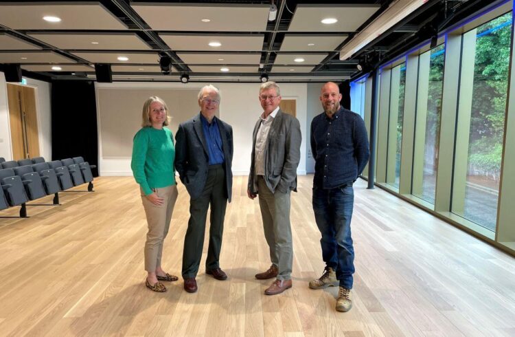 Four people pose inside a modern dance studio