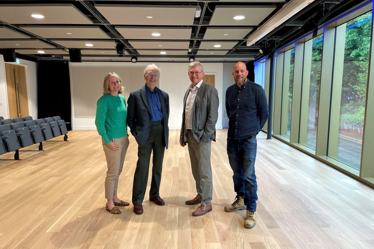 Four people pose inside a modern dance studio