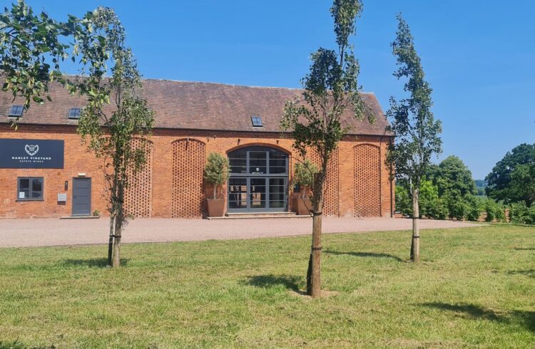 Exterior view of converted barn at Hanley Vineyard with grass and trees to front