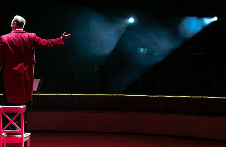 Circus ringmaster dressed in red facing the audience