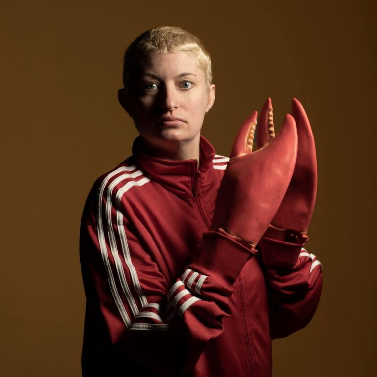 A person dressed in red with fake lobster claws on their hands