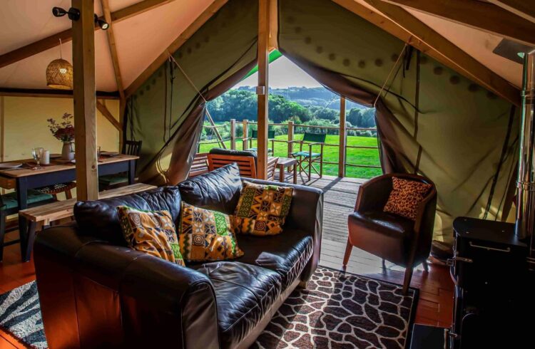 Interior of Hakuna Matata Safari Lodge with sofa, chair, dining area and views of countryside beyond