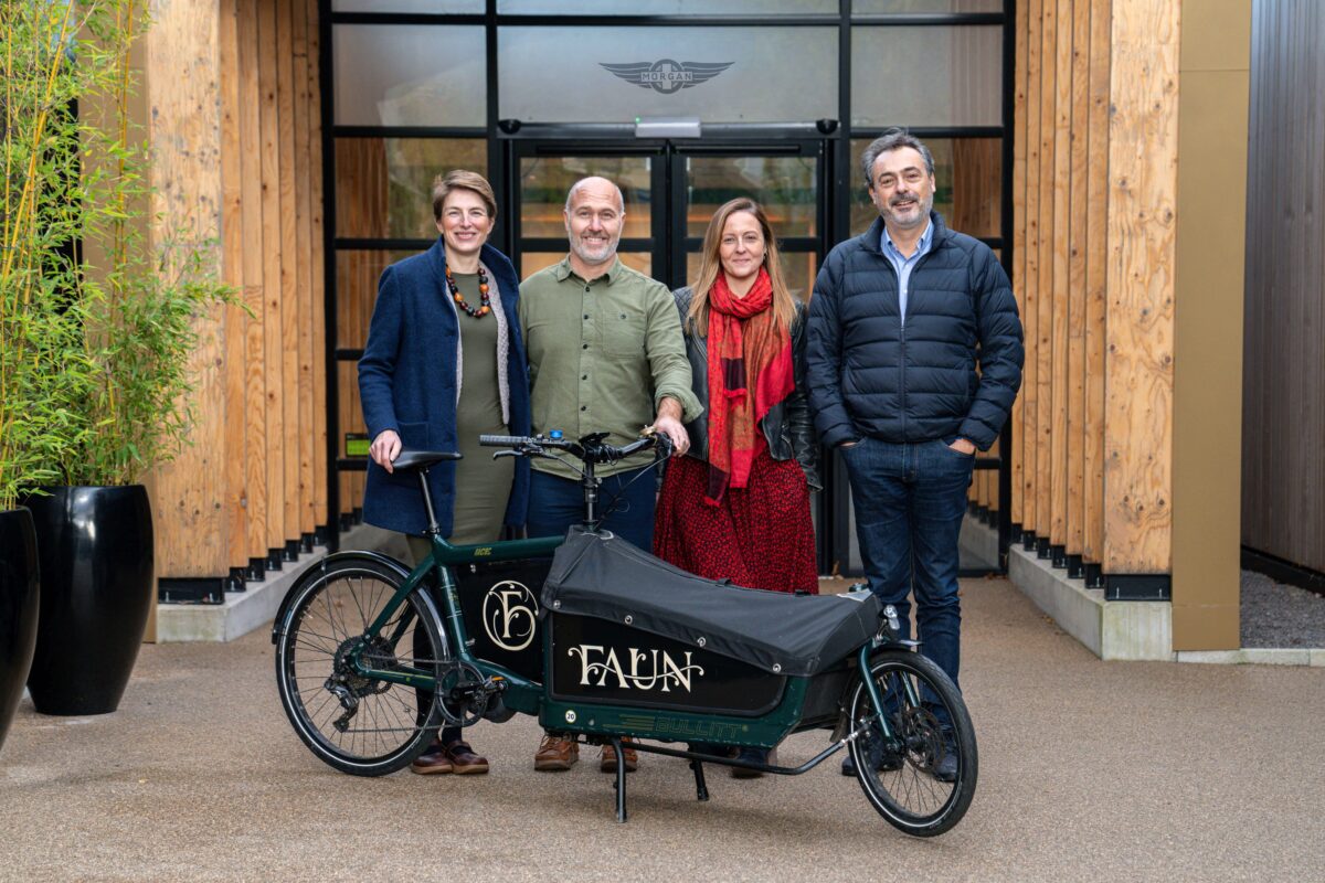 Four people stand outside a building with a cargo bike in front of them