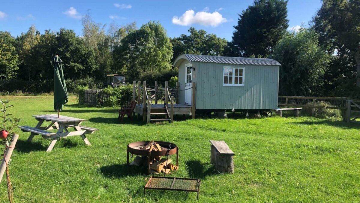 Exterior of hut with grass around, picnic bench and decking