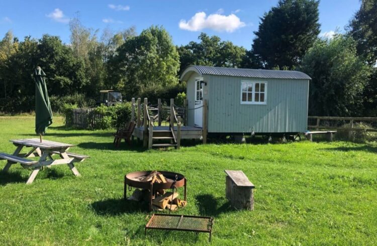 Exterior of hut with grass around, picnic bench and decking