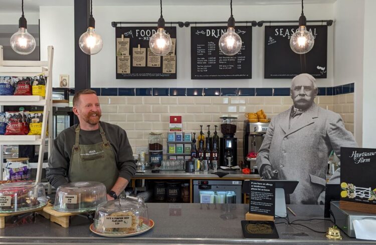 A man stands behind a cafe counter