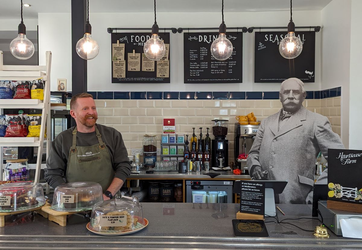 A man stands behind a cafe counter