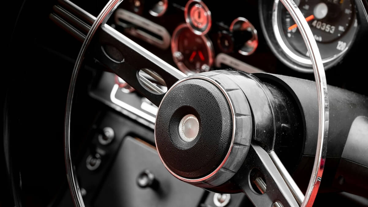 The interior of a classic car including steering wheel and instruments