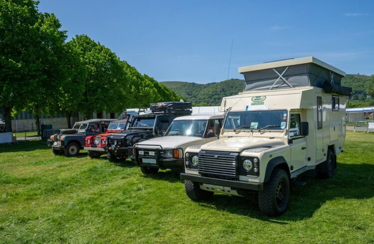 A variety of Land Rovers parked in a row with view of the Malvern Hills in the background