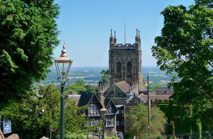 A view of a Victorian gas lamp in Rosebank Gardens, Malvern with Great Malvern Priory in the background against a blue sky