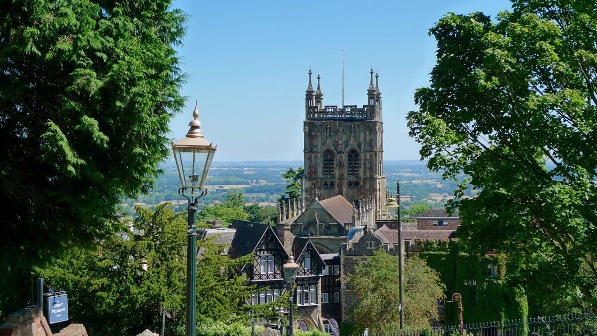 A view of a Victorian gas lamp in Rosebank Gardens, Malvern with Great Malvern Priory in the background against a blue sky