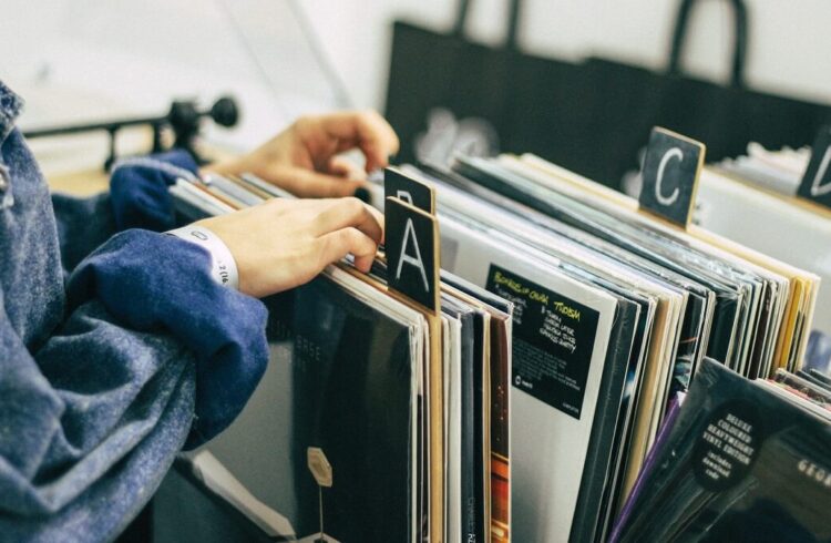 A person looking through vinyl records arranged alphabetically