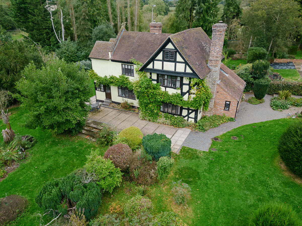 An aerial view of an English country house with green surrounding gardens and outbuildings