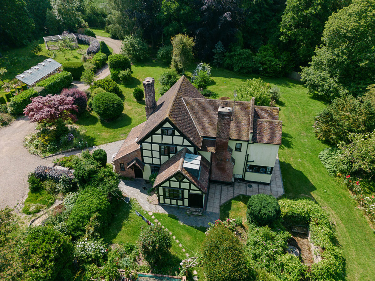 An aerial view of an English country house with green surrounding gardens and outbuildings