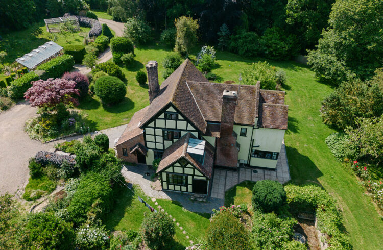 An aerial view of an English country house with green surrounding gardens and outbuildings