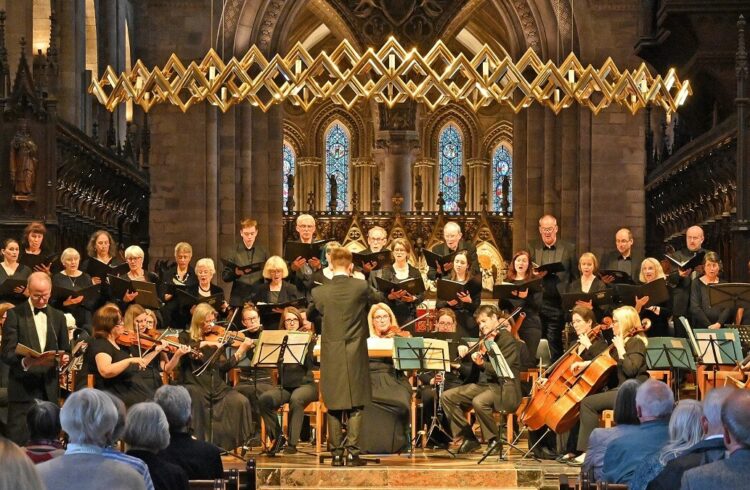 An audience watching a classical orchestra playing, with smartly choral singers behind