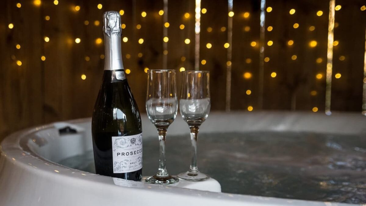 A bottle of Prosecco and two glasses by a hot tub