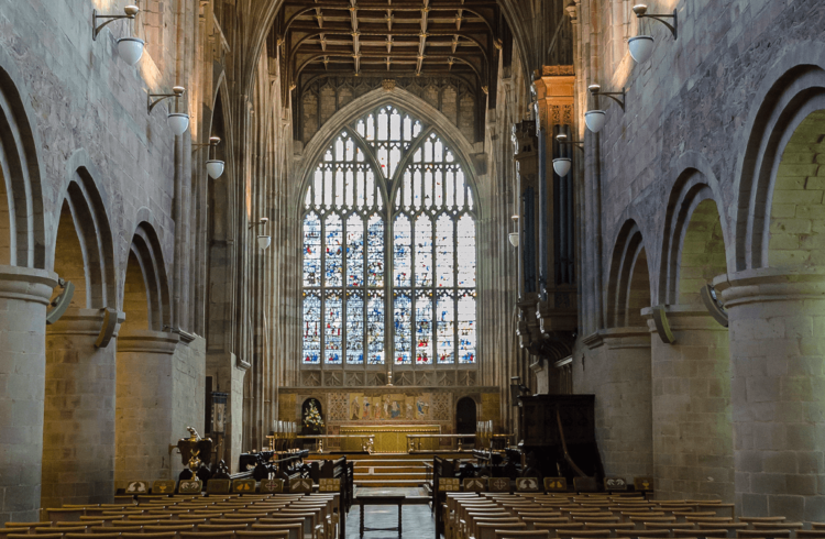 The interior of Great Malvern Priory with Norman pillars and large east window in stained glass