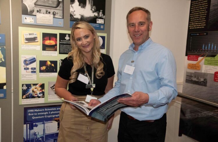 Two people read a leaflet and smile in front of a museum display