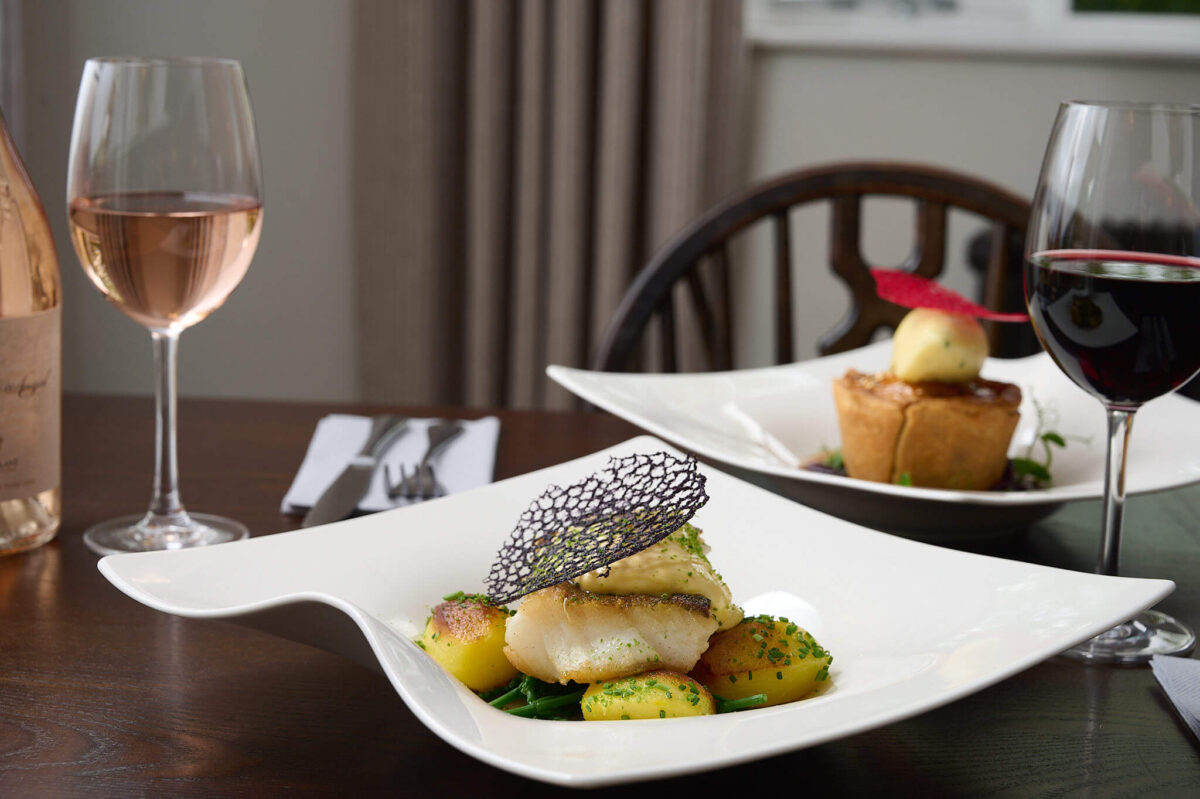 A fine dining style fish dish with a glass of wine