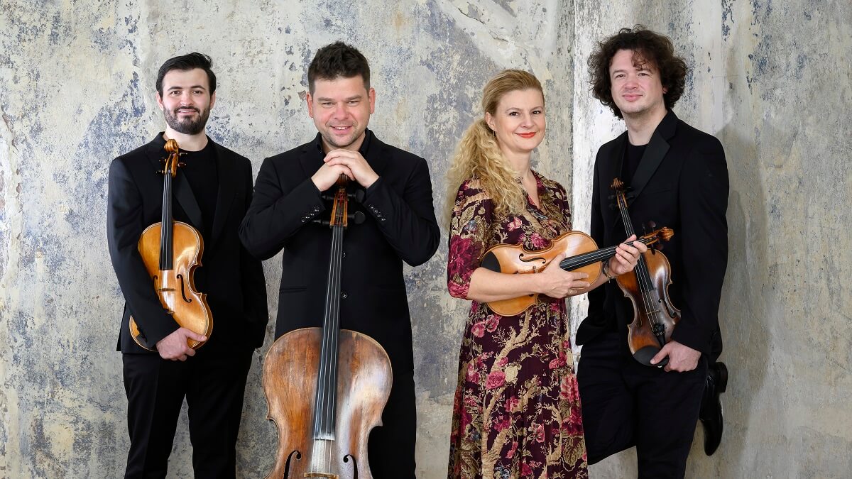 All four members of the Pavel Haas Quartet dressed for a concert and standing facing the camera